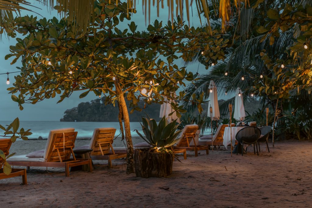 Beachfront lounge area with wooden chairs at Awā Beachfront Hotel, overlooking the Caribbean Sea in Punta Uva.